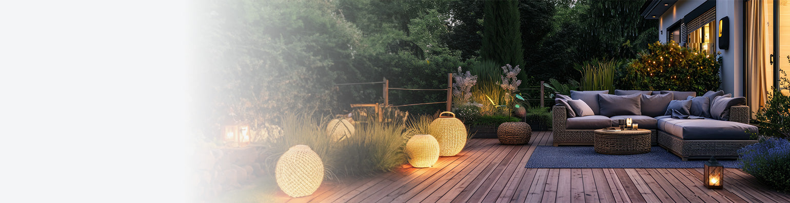 Eine sehr moderne Terrasse umgeben von Grün mit grauen Lounge-Möblen und verschiedener Gartenbeleuchtung.