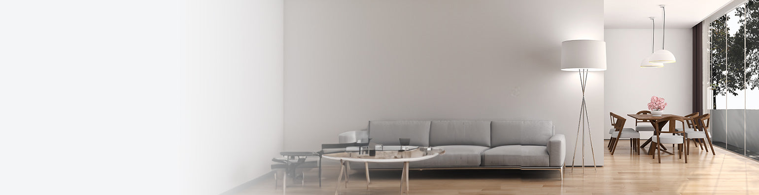 Sehr cleanes Wohnzimmer mit grauem Sofa, großer Standleuchte mit weißem Schirm und Esstisch an einer Fensterfront.