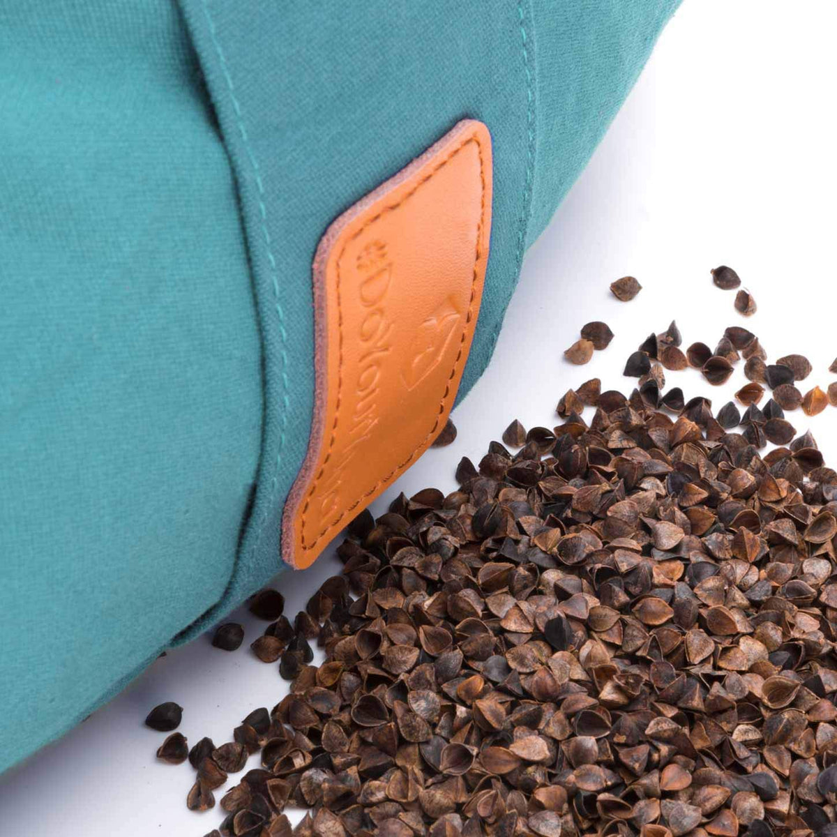 Bio-Buchweizenschalen zum Befüllen/Nachfüllen von Kissen & Bolstern - 5 kg mit ausgeschütteten Schalen neben einem Kissen