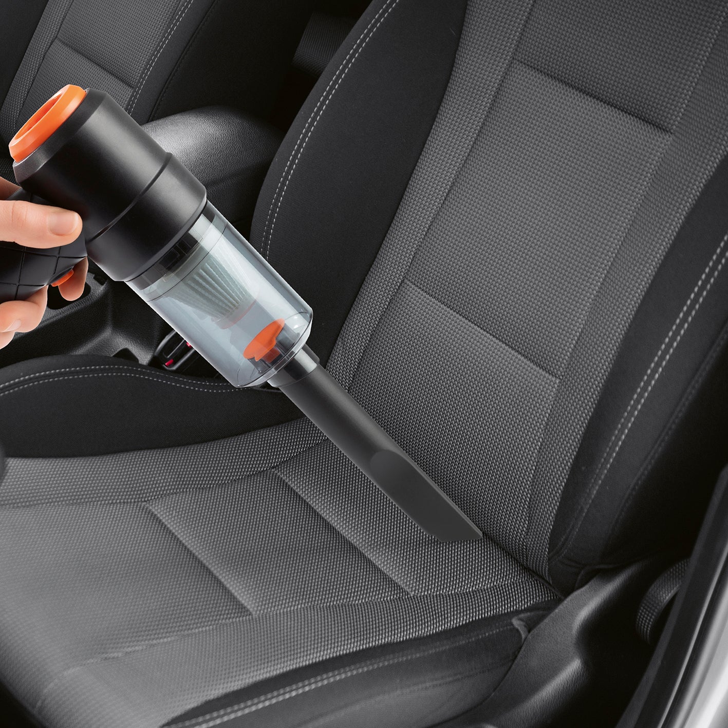 2in1-Akkusauger mit Saug- und Gebläsefunktion beim Reinigen von Autositzen mit schmaler Fugendüse und transparentem Staubbehälter.