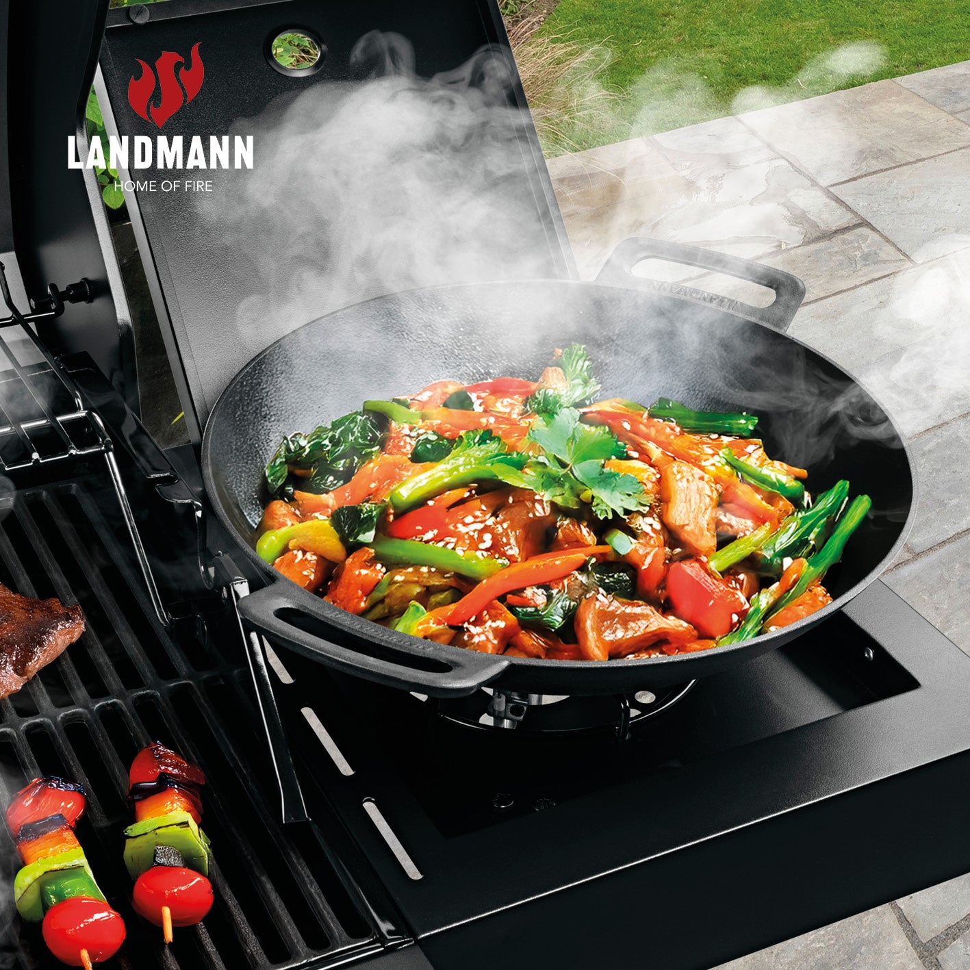 Gasgrill COOL BLACK 4.1 – 4 Brenner + Seitenbrenner mit wok auf dem Seitenbrenner frisch zubereitetes Gemüse und Grillspieße daneben
