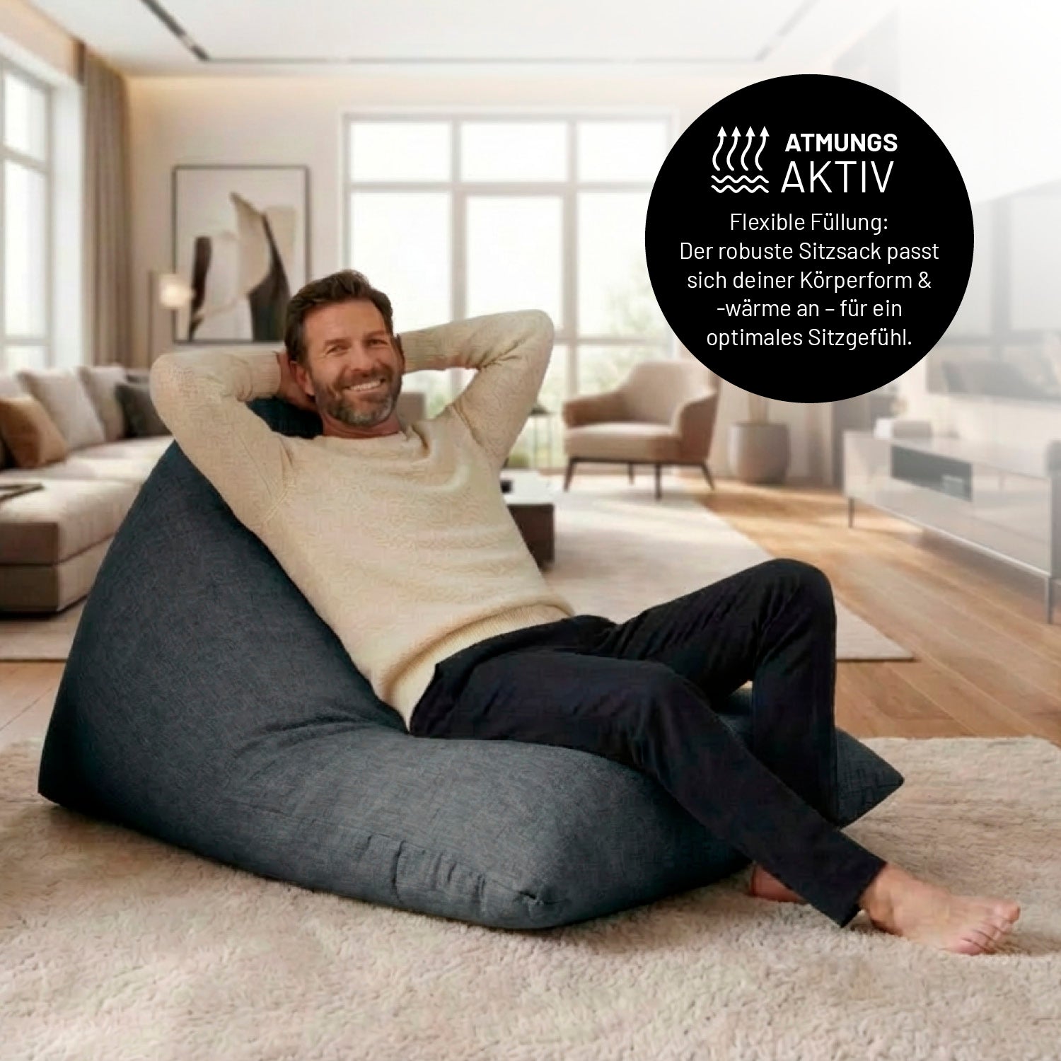 Mann entspannt auf Sitzsack Interior Line (370 L) - indoor - Dunkelgrau in modernem Wohnzimmer mit großem Fensterlicht.