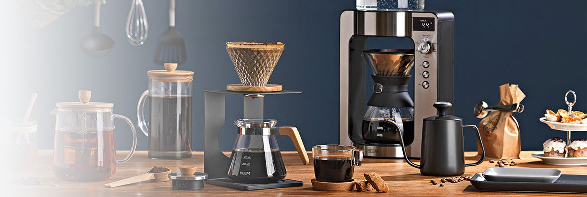 Verschiedene Produkte von BEEM auf einem Holztisch: Teekanne, Pour Over, Frensh Press, Kaffeemaschine und Kaffeemühle.