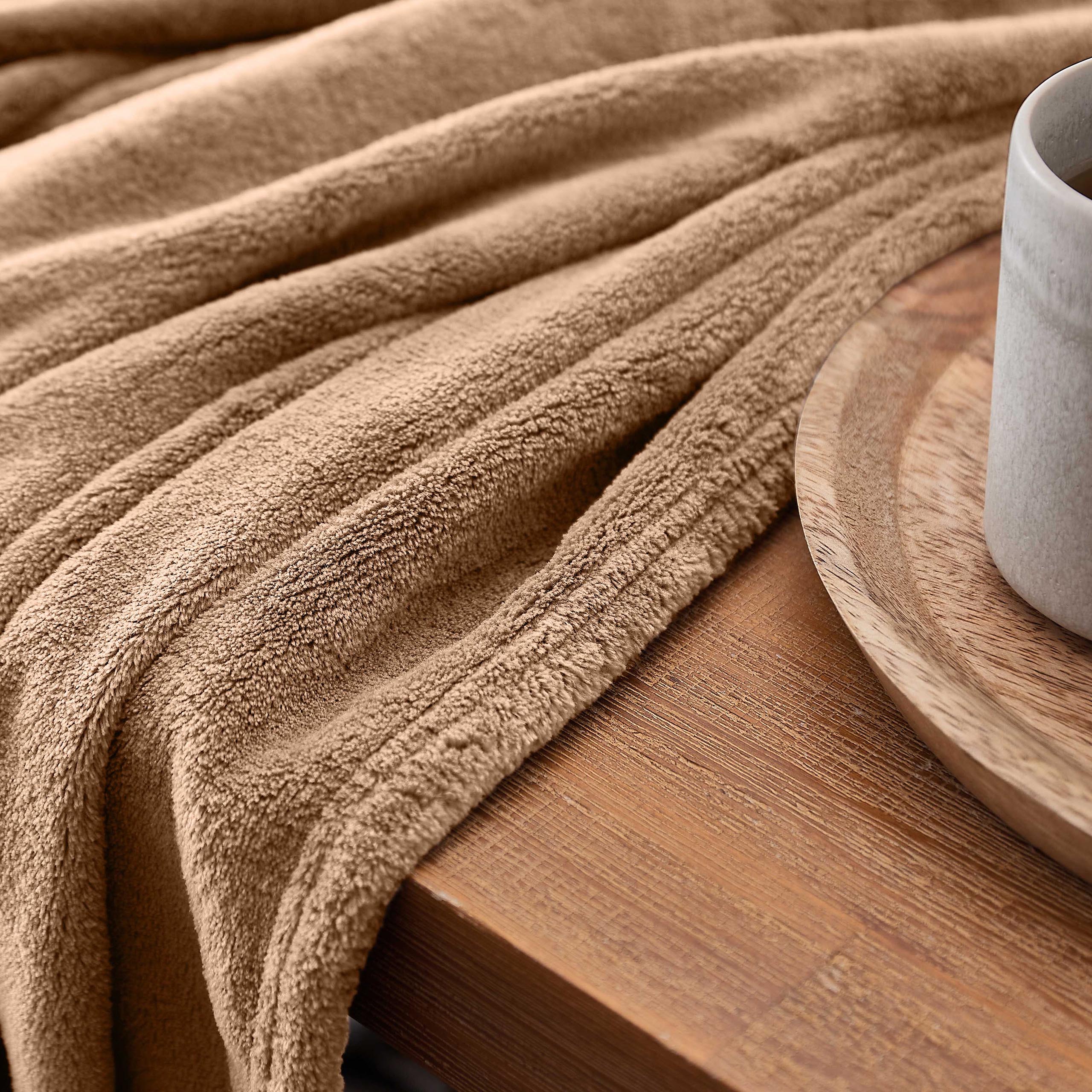 Kuscheldecke - 220x240 cm - Sofadecke & Tagesdecke - Hellbraun aus weichem Coral-Fleece auf Holztisch mit Kaffee.