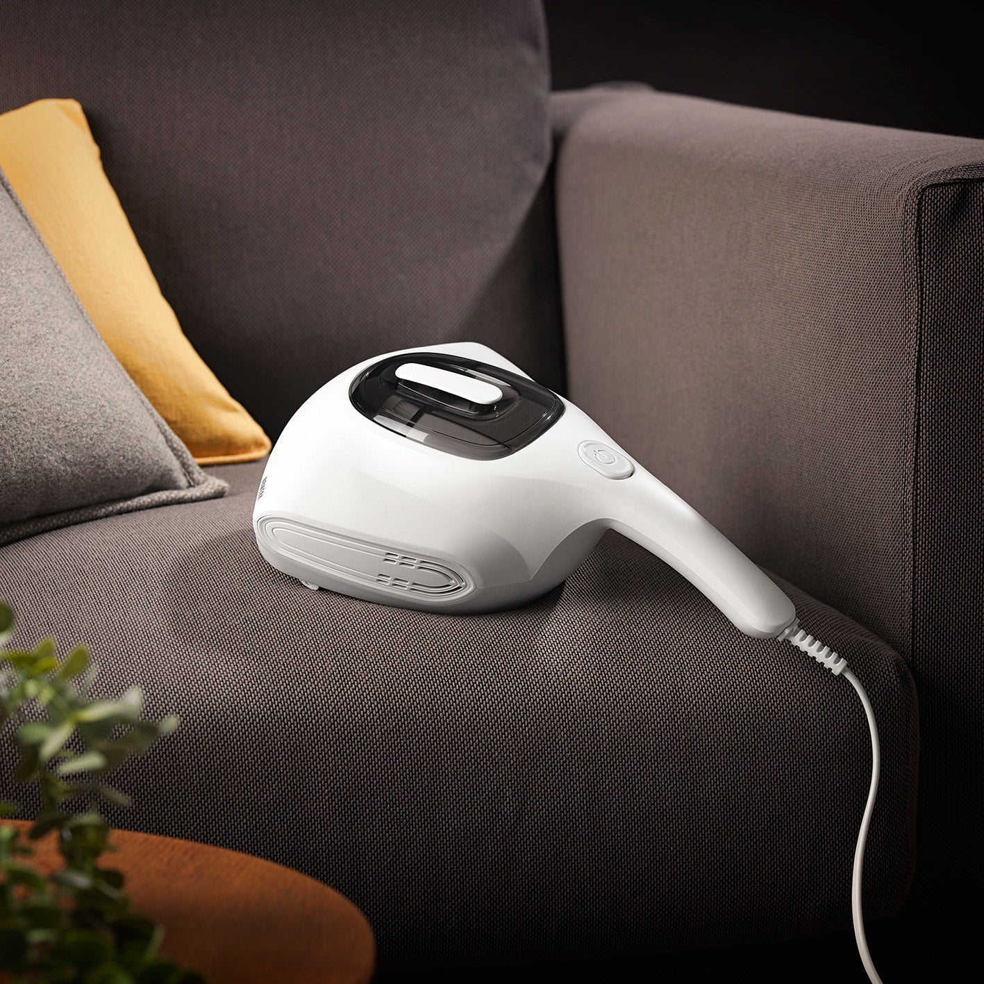 Milbensauger in der Moonlight Edition auf grauem Sofa, für staubfreie und sterilisierte Oberflächen mit UV-C-Licht und HEPA 11-Filter.