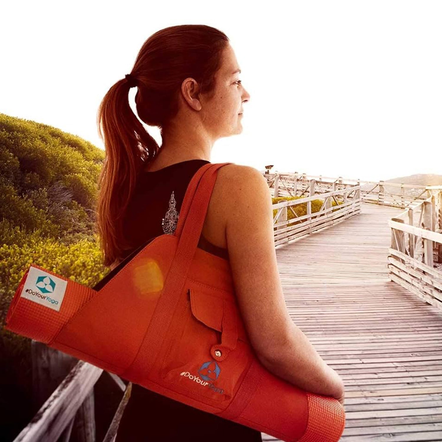 Frau trägt Yogamatte Ravana - 183 x 61 x 0,4cm mit Tragegurt, ideal für Yoga und Fitness unterwegs.