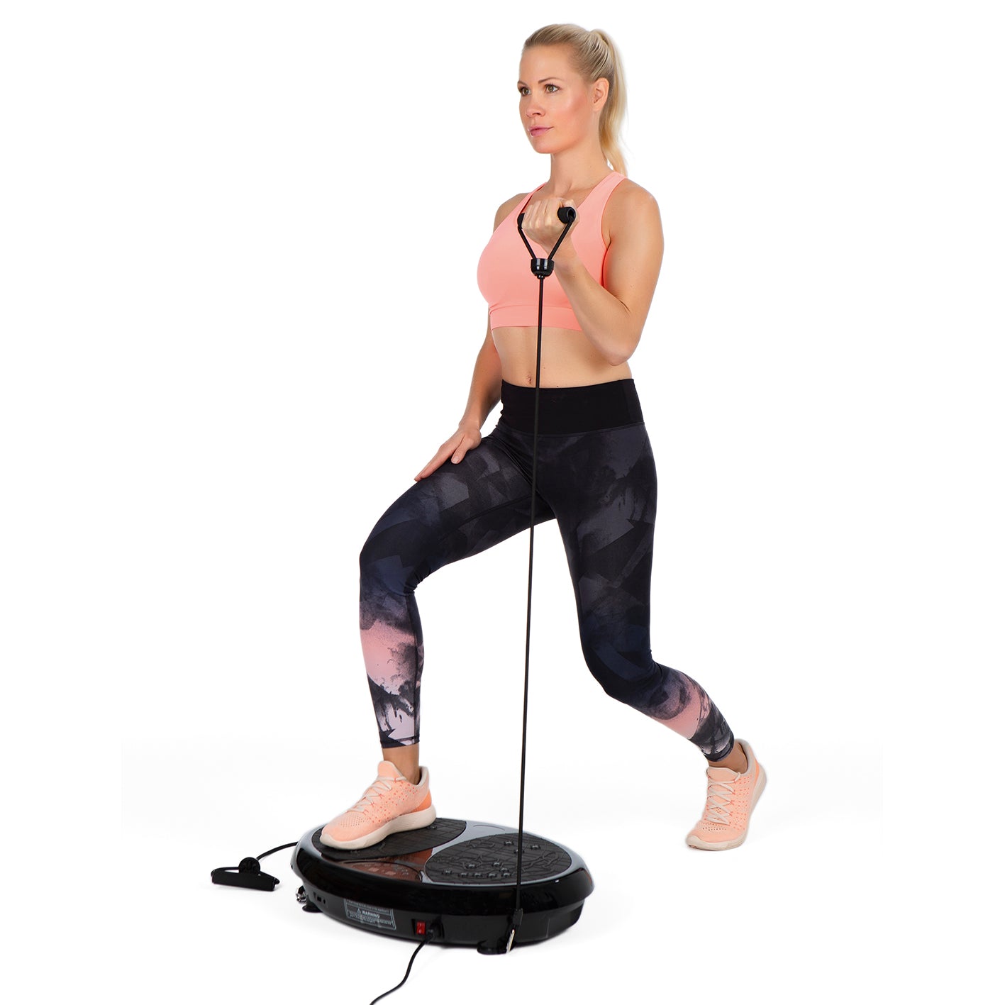 Frau trainiert mit Vibrationstrainer und Expanderbändern für Ganzkörpertraining zu Hause mit Fernbedienung und LED-Display
