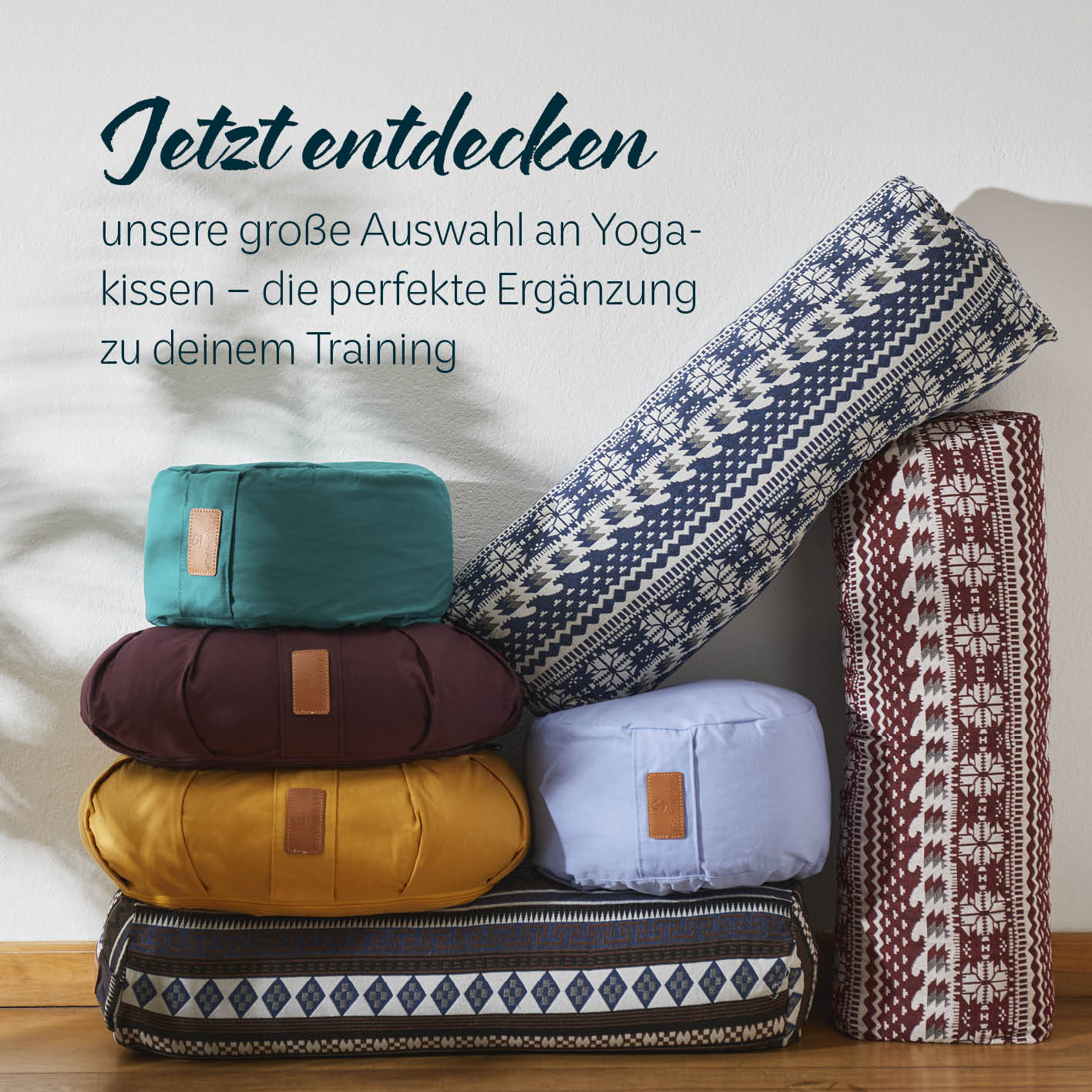 Yogamatte Kirana - 183 x 61 x 0,4 cm - Himbeerrot neben bunten Yoga-Kissen als perfekte Trainingsergänzung.