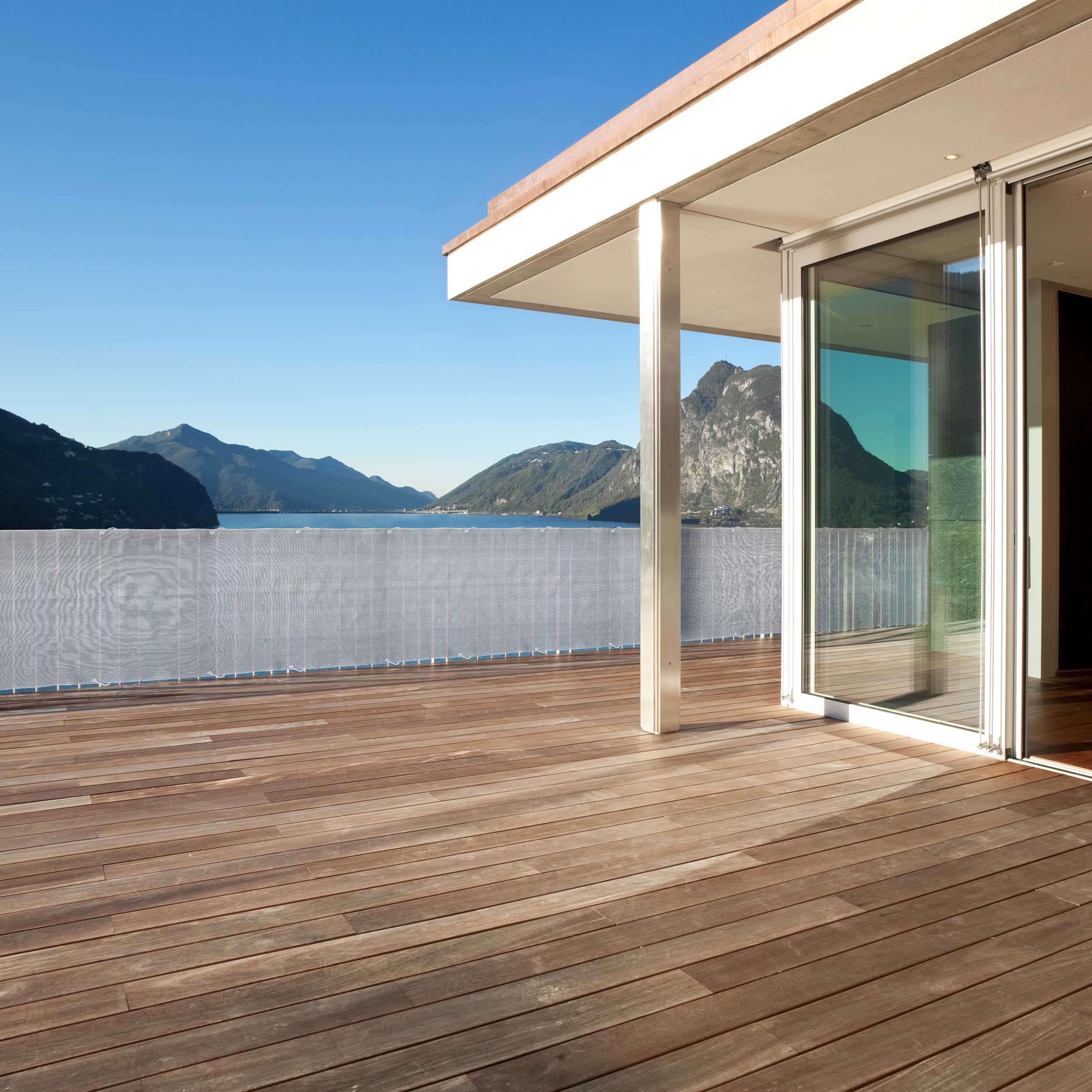 Balkonsichtschutz inkl. Befestigungsseil - 0,9 x 5 m - Hellgrau an moderner Balkonbrüstung mit Bergsicht und Holzterrasse.