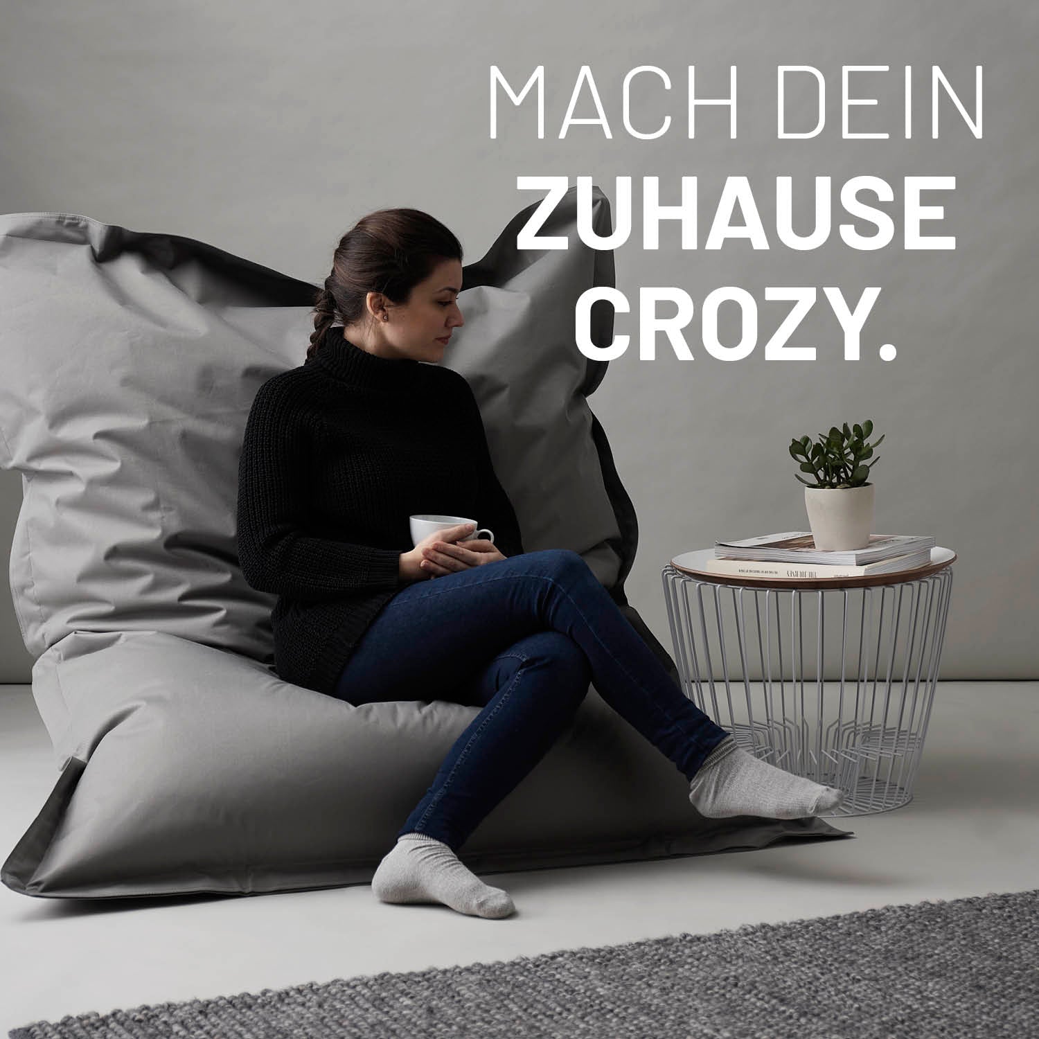 Frau sitzt entspannt auf Sitzsack Classic XXL (380 L) - indoor & outdoor - Pastell Grün in modernem Ambiente.