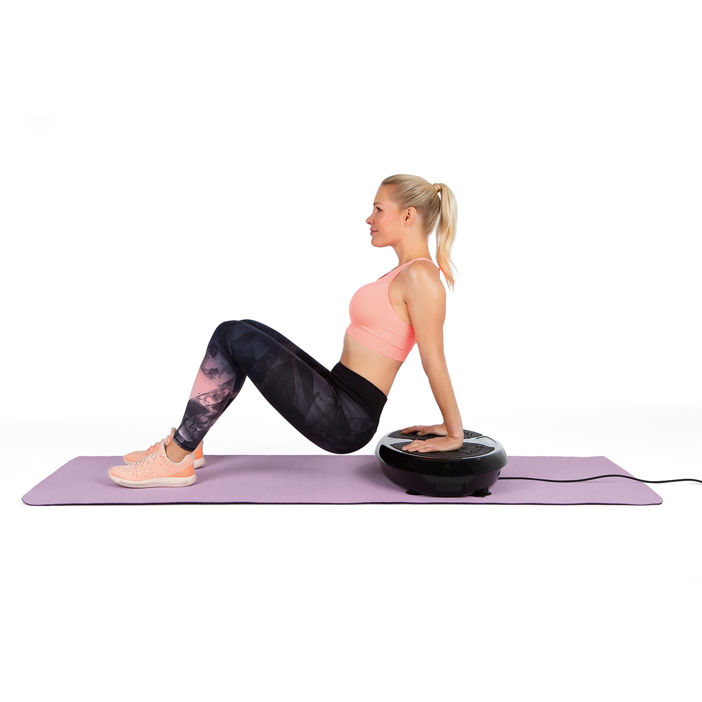 Frau trainiert auf Vibrationstrainer mit rutschfester Fläche auf Yogamatte, Ganzkörpertraining zu Hause.