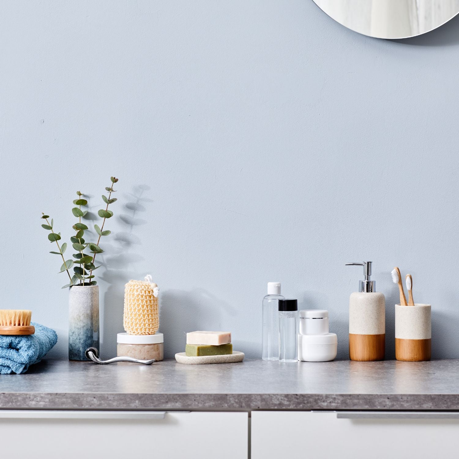 Minimalistisch eingerichtete Badezimmerablage mit Seifen, Spendern, Zahnbürsten und Pflanzen für stilvolle Ordnung.