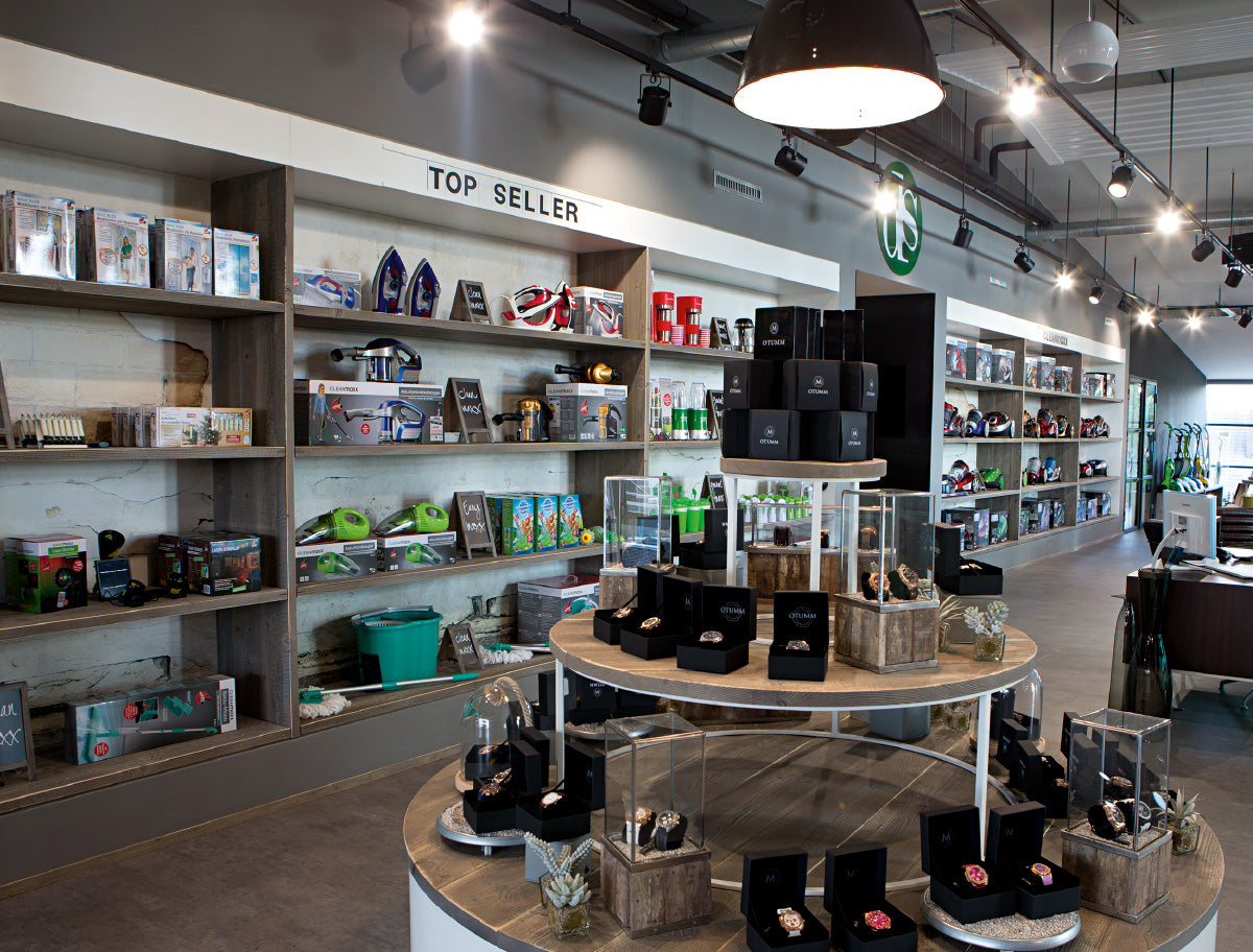 Moderner Showroom der DS Produkte GmbH mit Regalen voller Topseller, Haushaltswaren und Uhren in stilvoller Präsentation.