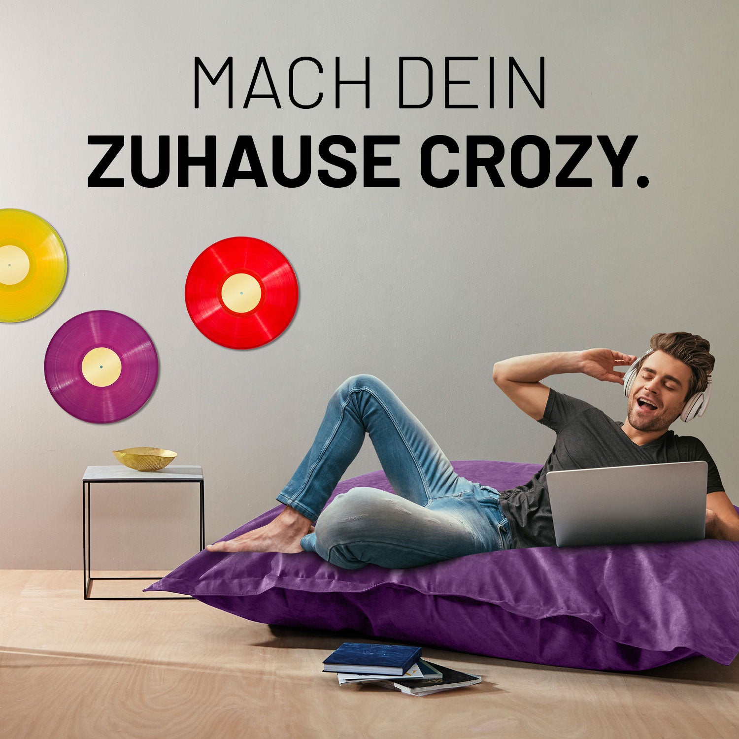 XXL Microvelours Sitzsack (380 L) - indoor - Lila mit entspanntem Mann liegend und Laptop im modernen Wohnzimmer.