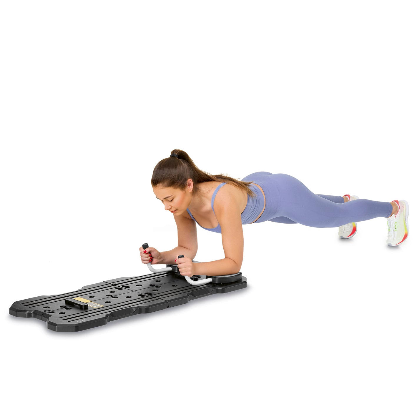 Frau trainiert mit Pilates Reformer Fitnessboard - faltbar in Bauchlage, hält Griffe für Stabilität beim Workout.